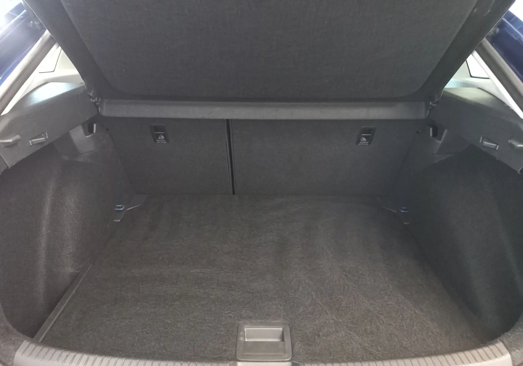 Coffre ouvert vu de l'arrière d'un Volkswagen Taigo 2025 bleu récif, montrant un espace de chargement propre et spacieux.
