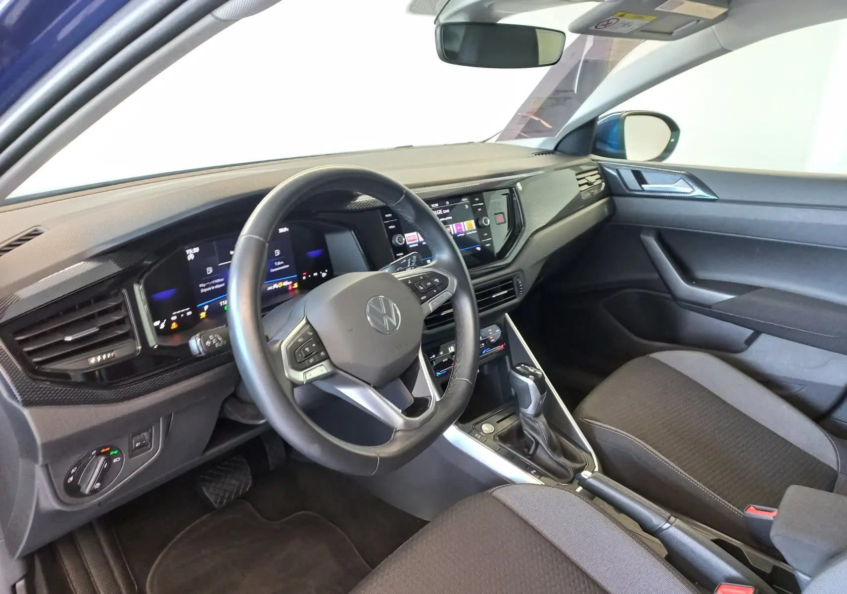 Vue intérieure côté conducteur du Volkswagen Taigo 2025 bleu récif, avec tableau de bord numérique et console centrale moderne.