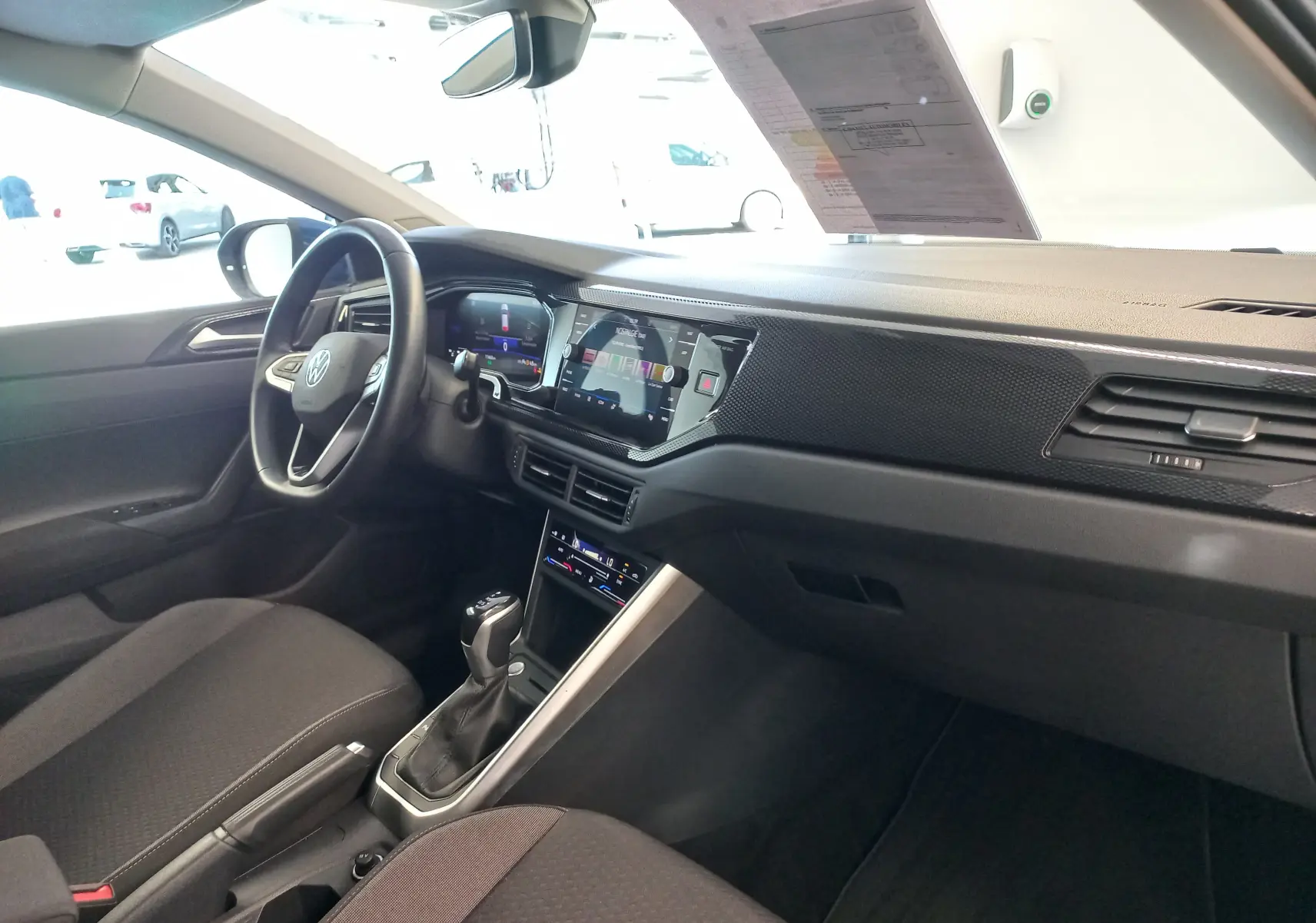 Vue intérieure côté conducteur du Volkswagen Taigo bleu récif 2025, avec tableau de bord numérique et console centrale moderne.