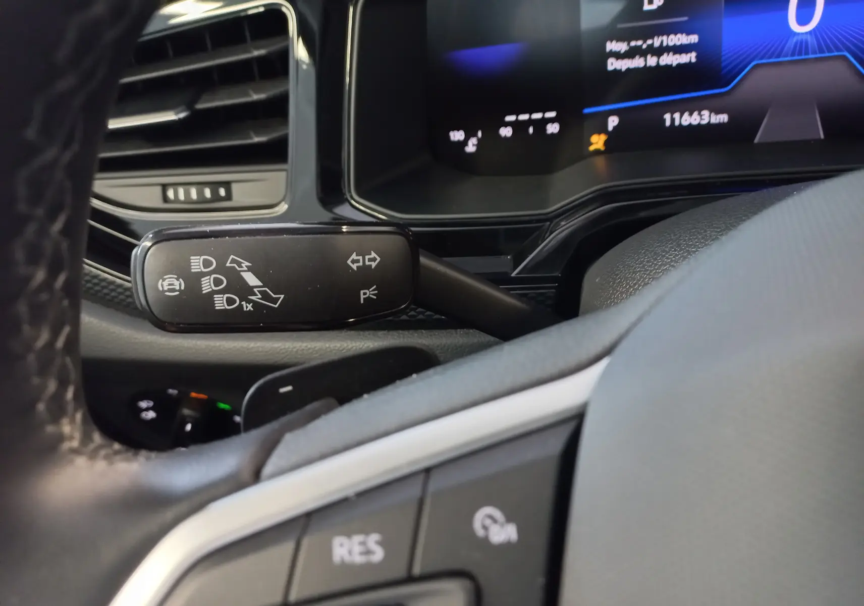 Gros plan sur la manette de clignotants et le tableau de bord numérique du Volkswagen Taigo 2025, intérieur noir.