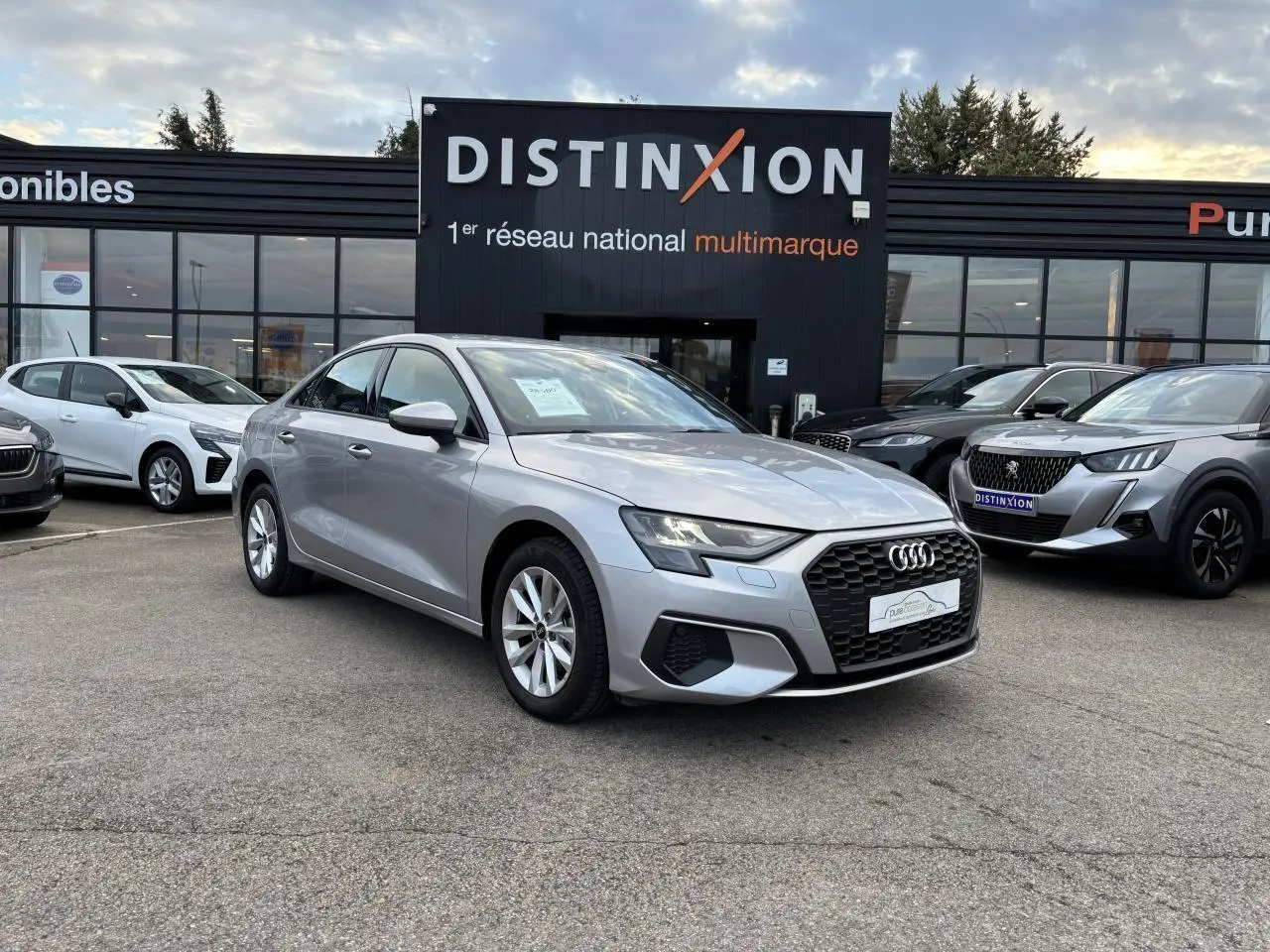 Audi A3 berline argent métallisé vue 3/4 avant, avec calandre hexagonale noire et jantes alliage 5 branches.