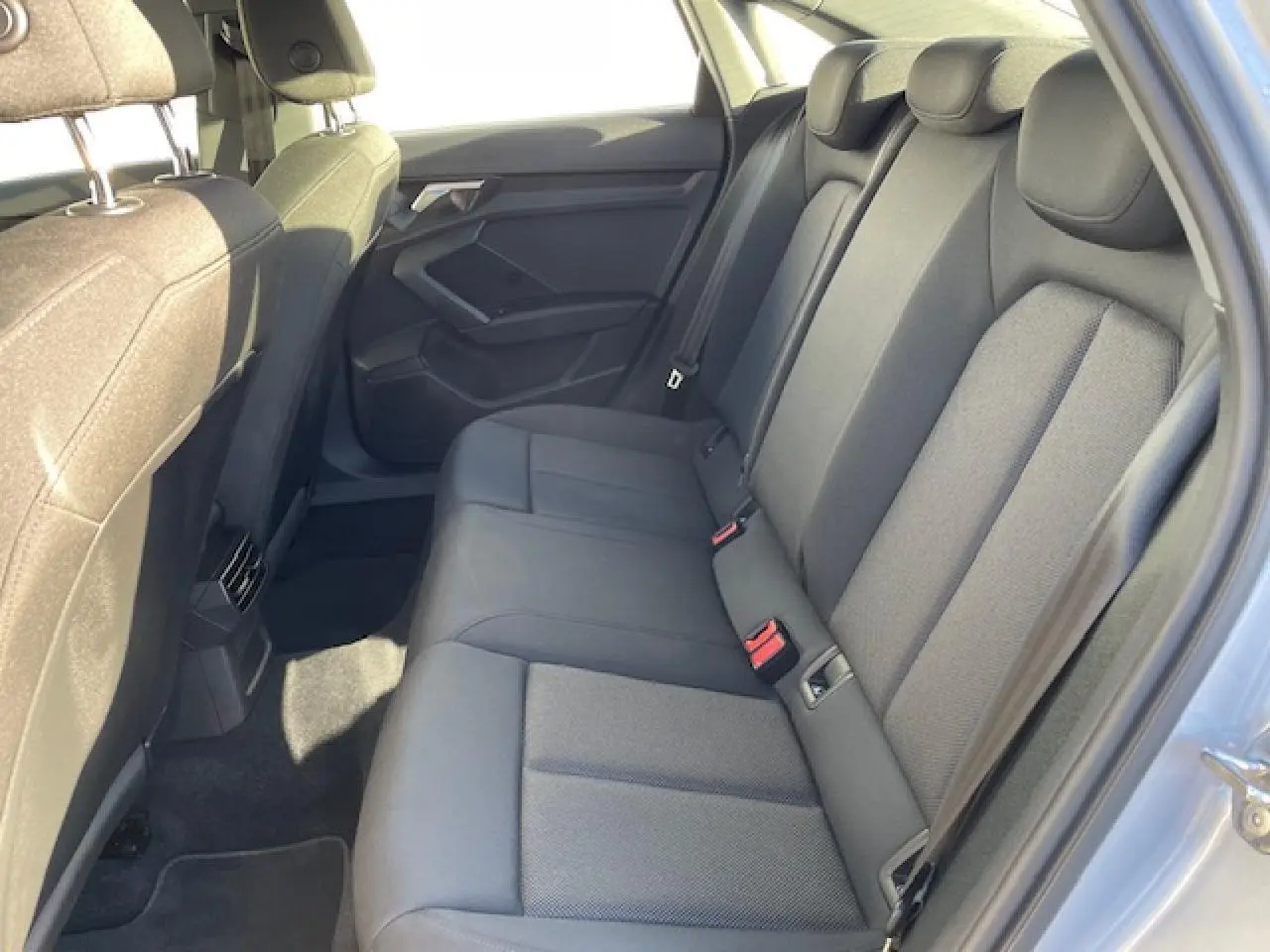 Vue latérale droite de l'habitacle arrière de l'Audi A3 2022 avec sièges tissu gris et ceintures de sécurité visibles.