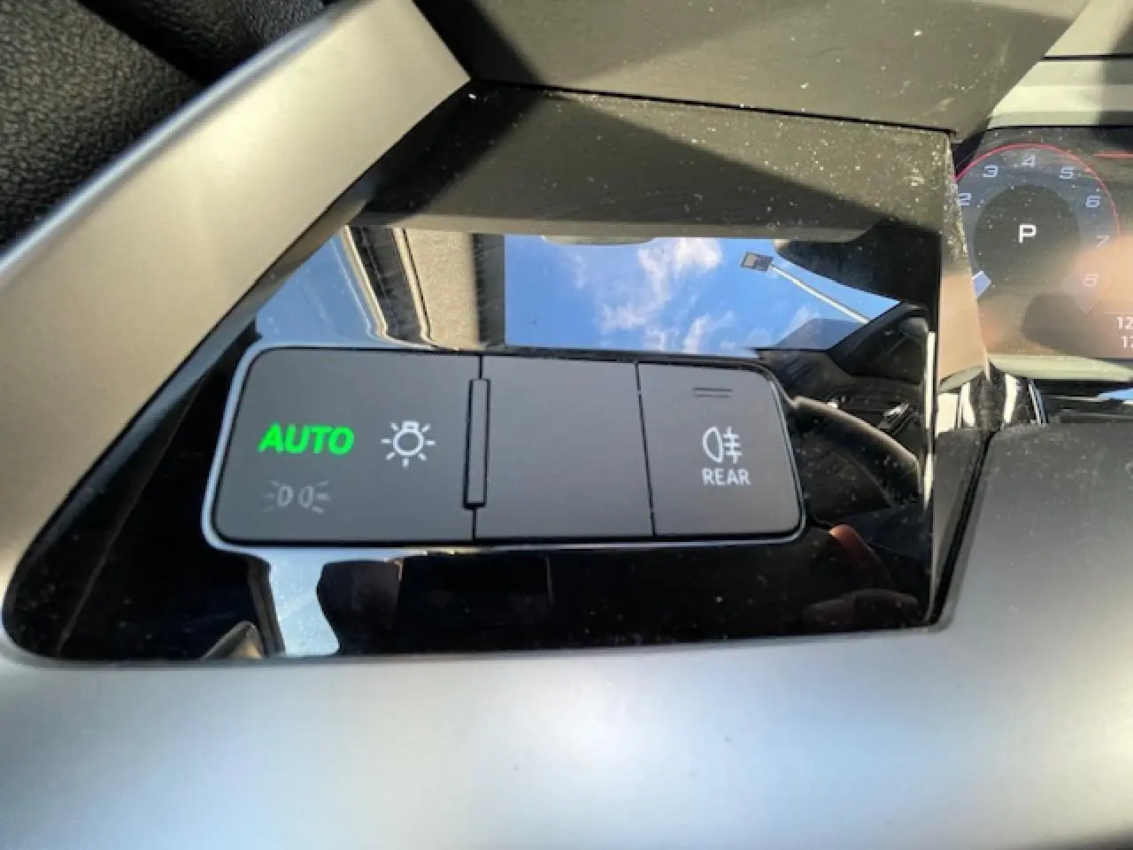 Gros plan sur les commandes d'éclairage avec mode auto activé dans l'habitacle de l'Audi A3 argent fleuret métal 2022.