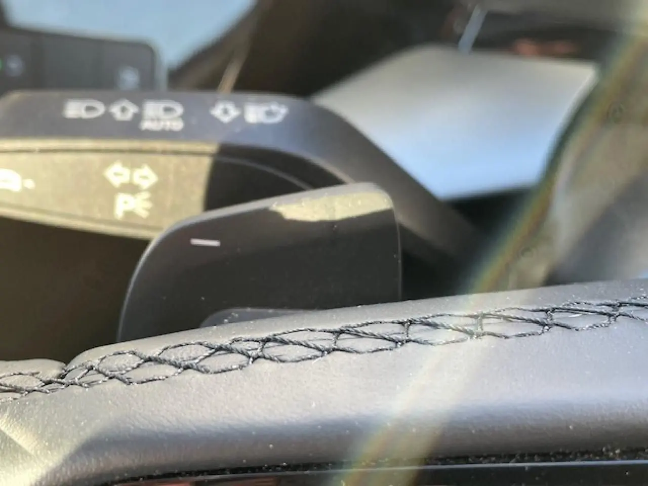 Gros plan sur la palette de changement de vitesses et le volant cuir noir de l'Audi A3 IV Berline 2022.