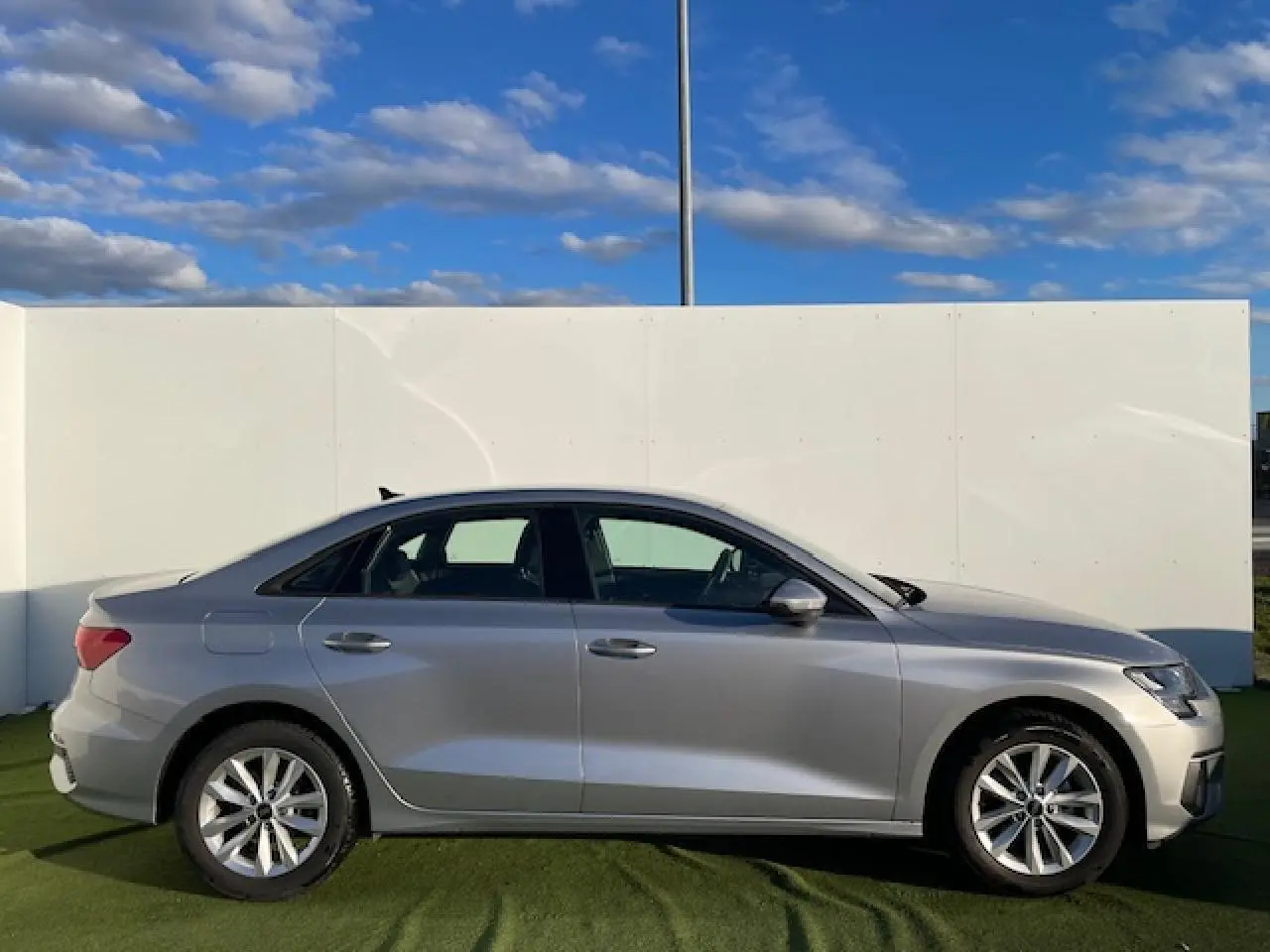 Profil côté gauche d'une Audi A3 berline 2022 argent métallisé avec jantes alliage 5 branches parallèles.