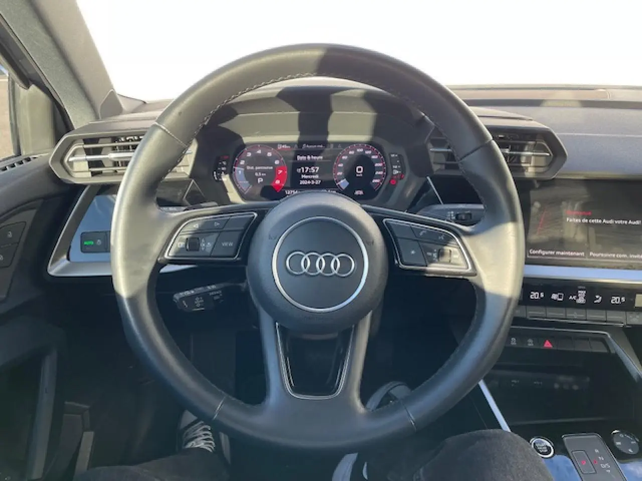 Vue centrée sur le volant cuir multifonctions de l'Audi A3 2022 avec tableau de bord digital et écran tactile.