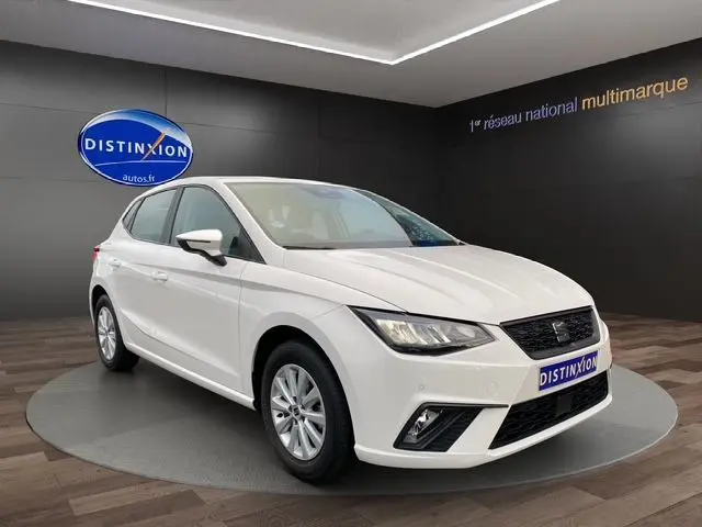 SEAT Ibiza 1.0 MPI 80 STYLE blanc candy vue 3/4 avant droit en showroom avec logo Distinxion en arrière-plan