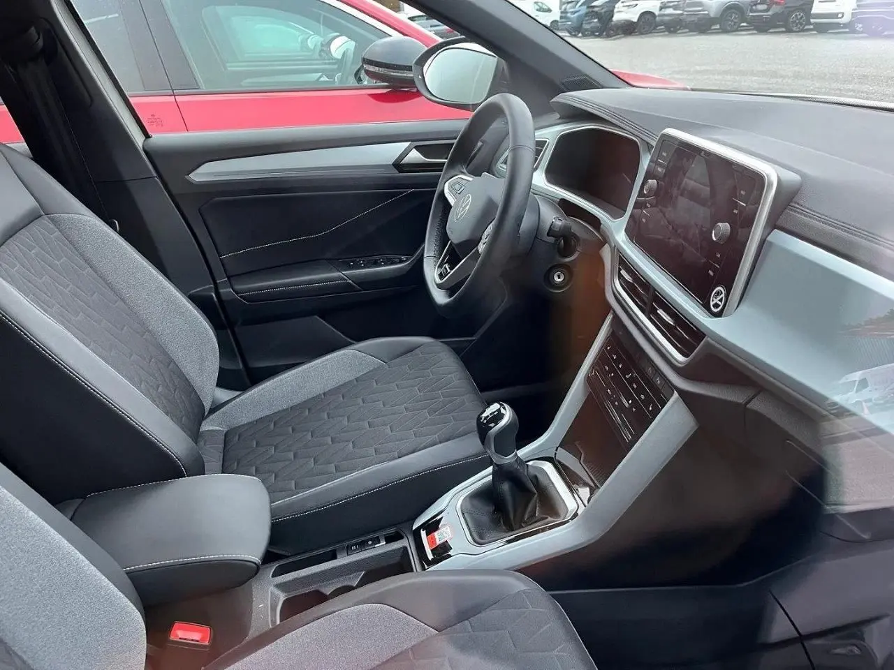 Intérieur du Volkswagen T-Roc 2.0 TDI 116CH Life Plus 2025, vue côté conducteur, sièges tissu gris et console centrale avec boîte manuelle.