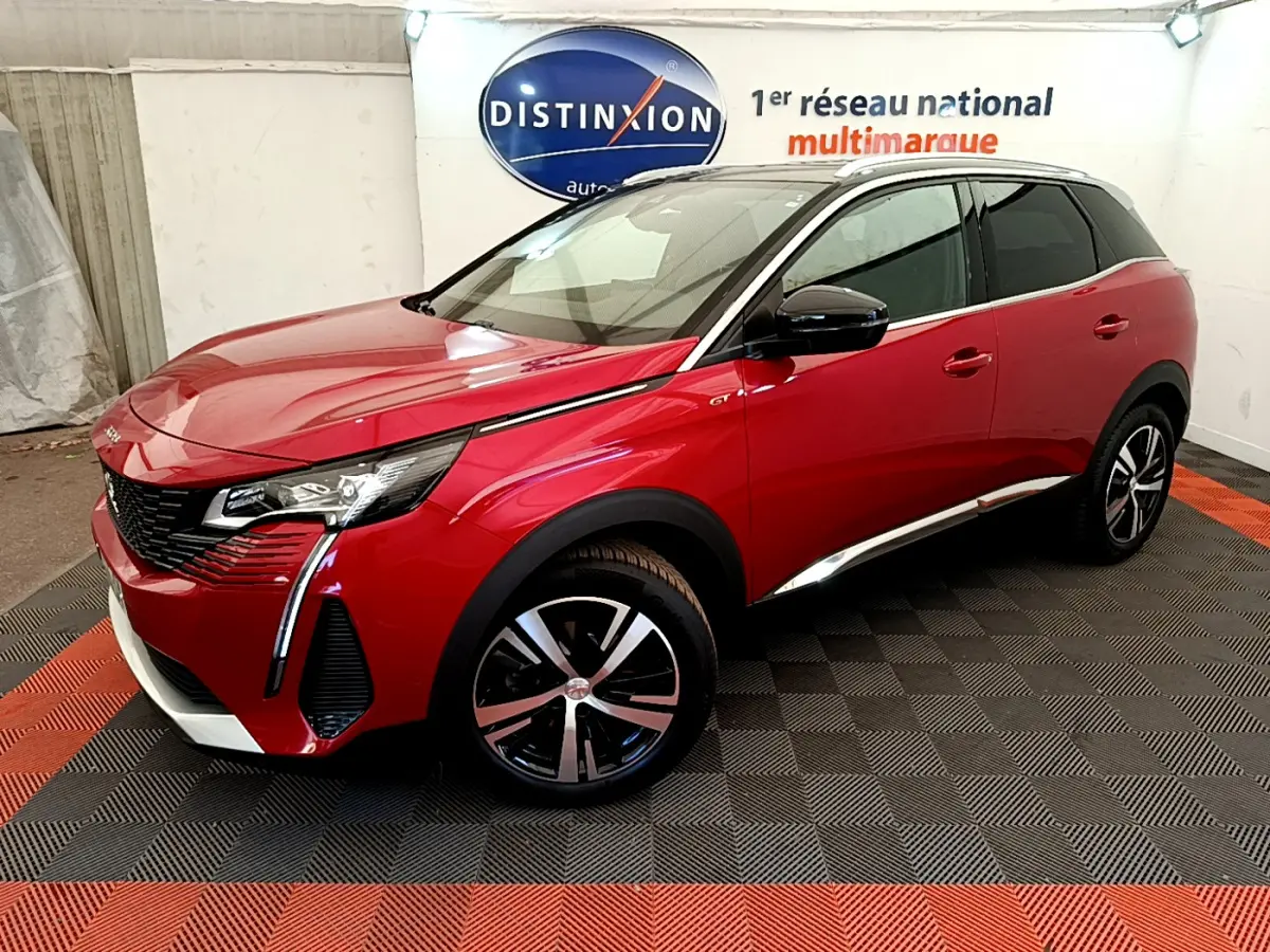Vue 3/4 avant droite d'un Peugeot 3008 GT rouge avec toit noir et jantes alliage bicolores en intérieur showroom.