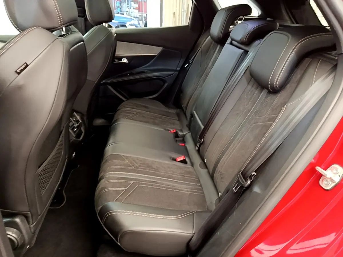 Vue intérieure côté droit des sièges arrière en cuir et alcantara noirs du Peugeot 3008 GT rouge de 2021 avec surpiqûres contrastées.