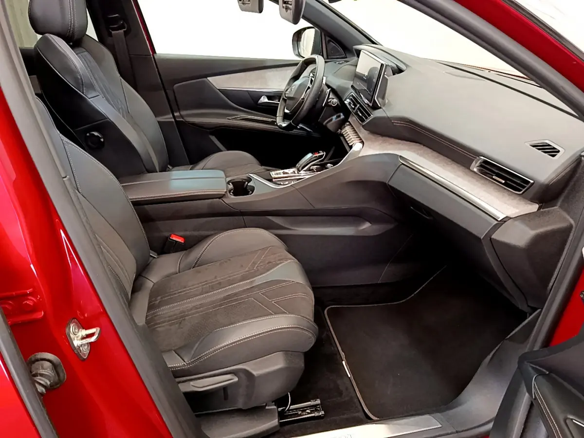 Intérieur avant droit du Peugeot 3008 GT rouge 2021, sièges cuir et alcantara, tableau de bord moderne avec écran tactile.