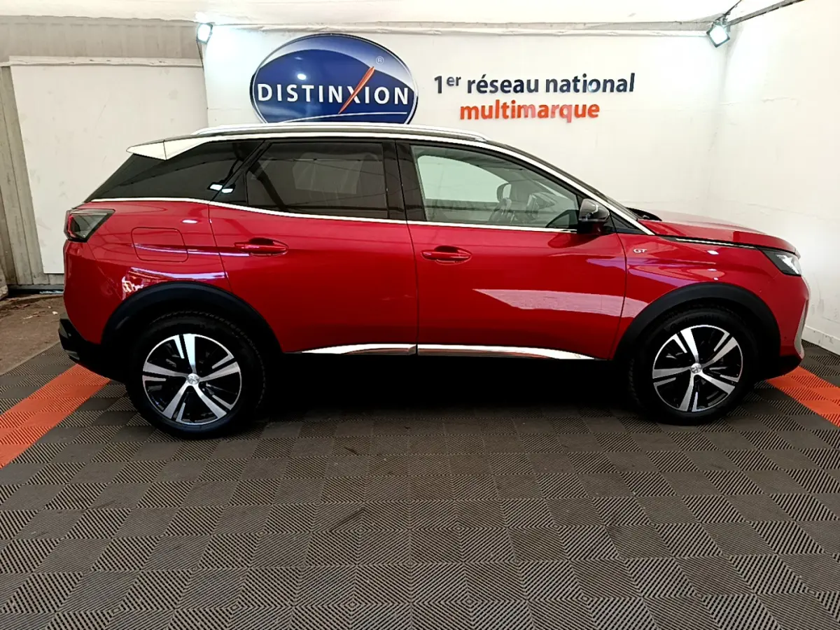 Profil côté droit d'un Peugeot 3008 GT rouge 2021, avec jantes alliage noires et toit blanc contrasté.