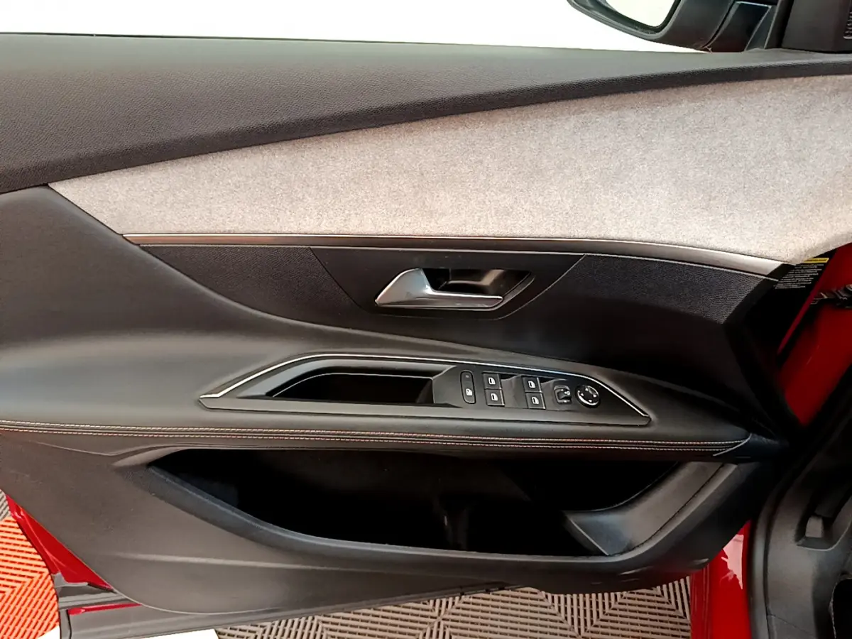 Vue rapprochée de la porte avant gauche rouge du Peugeot 3008 GT avec commandes de vitres et poignée argentée.