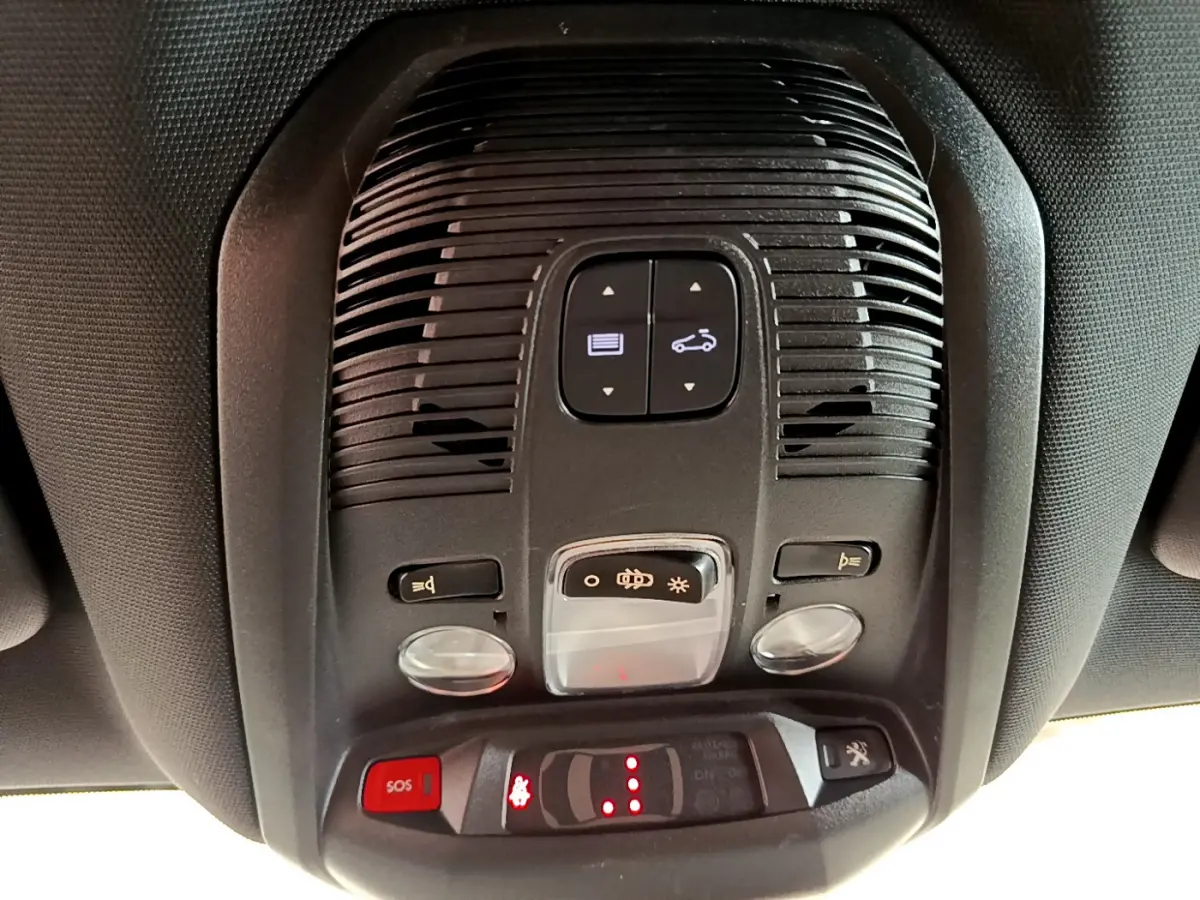 Vue en gros plan du plafonnier intérieur du Peugeot 3008 GT rouge, avec commandes d'éclairage et bouton SOS rouge.