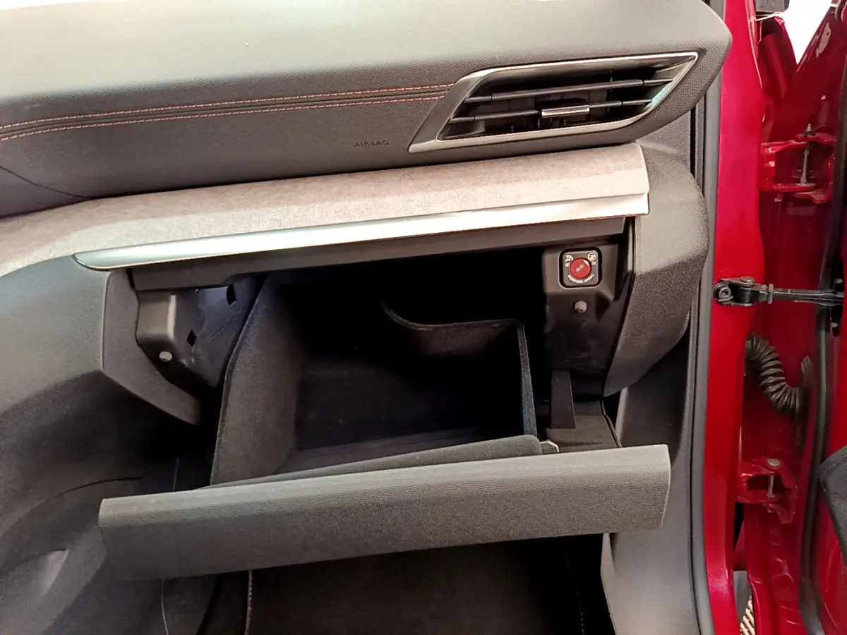 Intérieur Peugeot 3008 GT 2021 rouge, vue côté passager sur boîte à gants ouverte et tableau de bord noir avec surpiqûres rouges.