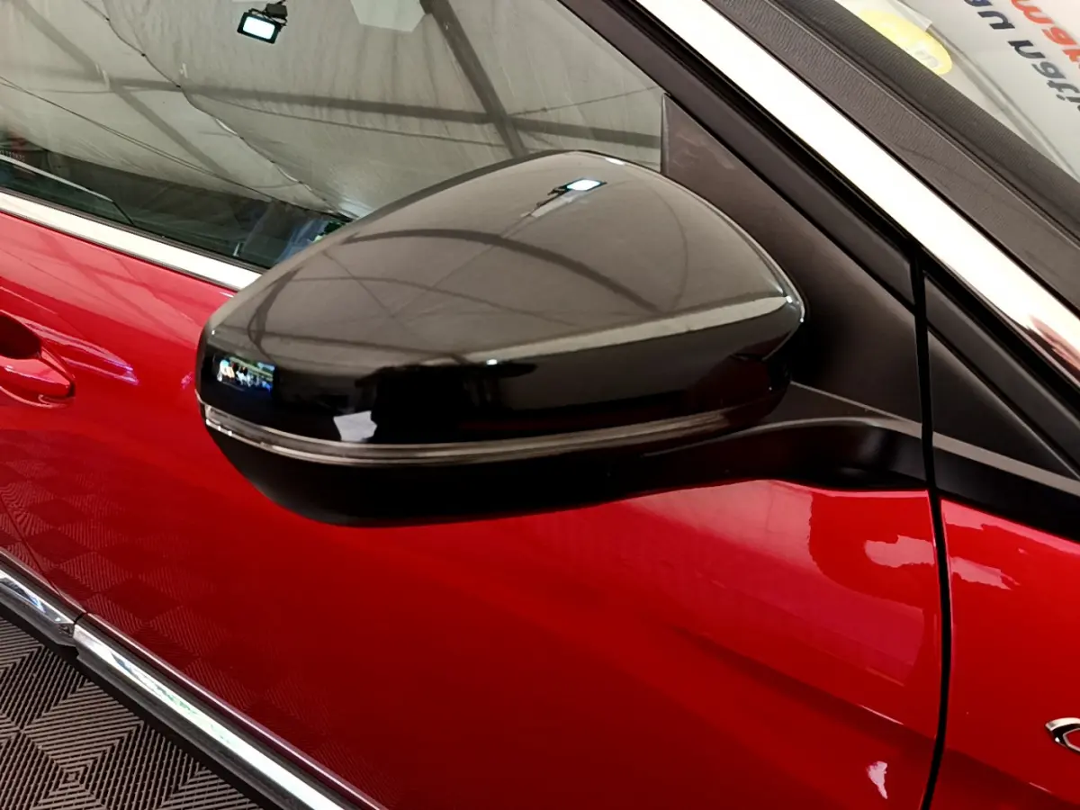 Gros plan sur le rétroviseur noir côté gauche du Peugeot 3008 GT rouge, mettant en valeur son design lisse et brillant.