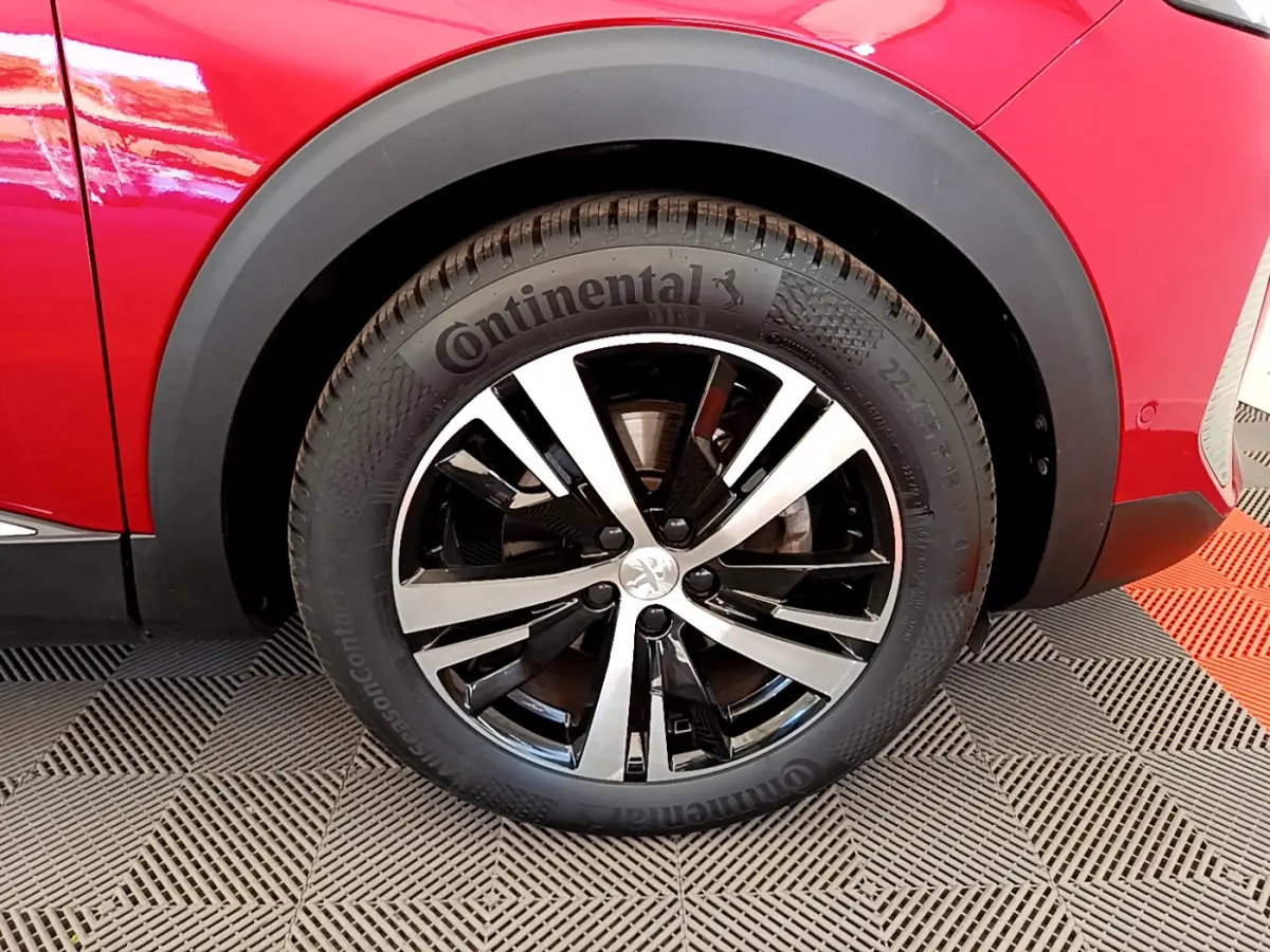 Gros plan sur la roue avant gauche du Peugeot 3008 GT rouge de 2021 avec jante alliage bicolore et pneu Continental.