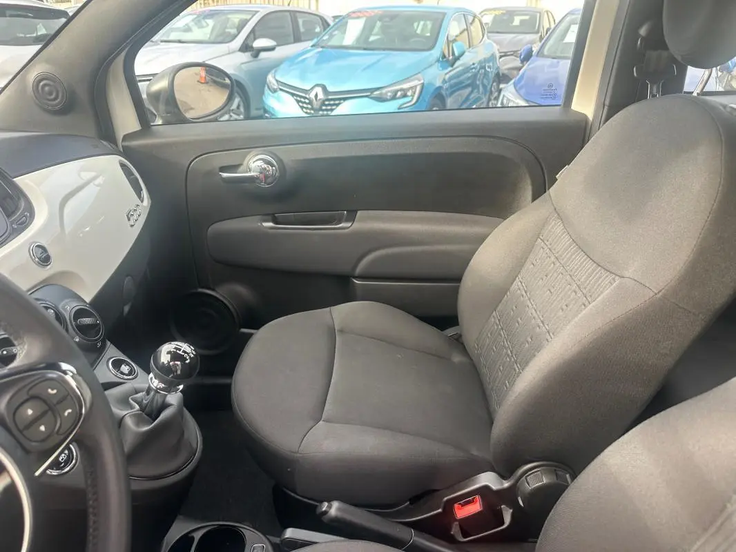 Intérieur côté passager du Fiat 500 blanc 2023, avec levier de vitesses manuel visible côté conducteur.