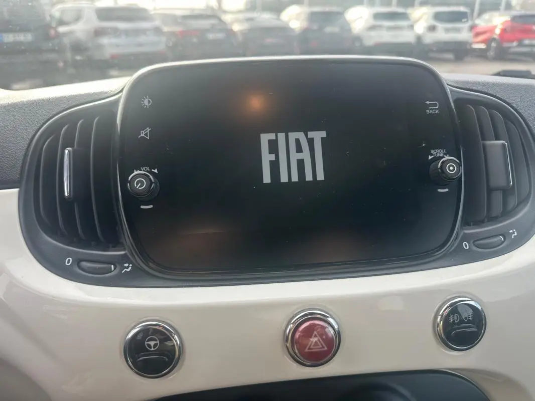 Écran central FIAT allumé avec logo, entouré de commandes et tableau de bord blanc d'une Fiat 500 2023.