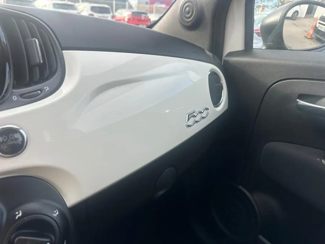 Vue intérieure côté passager du tableau de bord blanc brillant d'une Fiat 500 avec logo 500 visible sur la planche.