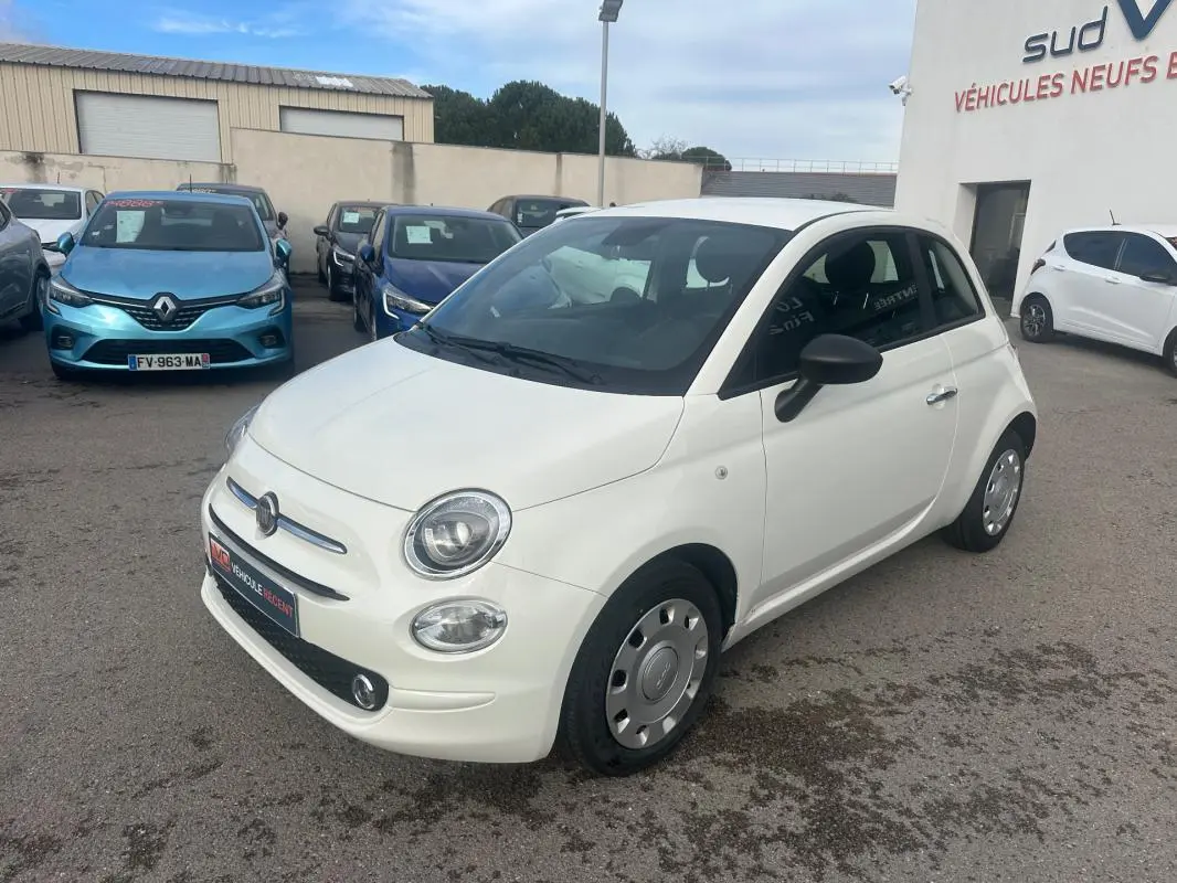 Vue 3/4 avant droite d'une FIAT 500 blanche 2023, avec ses phares ronds caractéristiques et jantes acier d'origine.