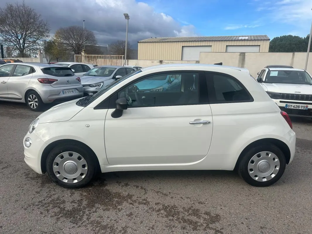 Profil côté gauche d'une FIAT 500 blanche de 2023, compacte et arrondie, avec jantes acier et rétroviseurs noirs.