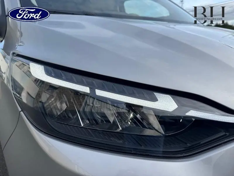 Gros plan sur le phare avant droit du Ford Transit Custom gris lunaire métallisé, avec détails LED visibles.