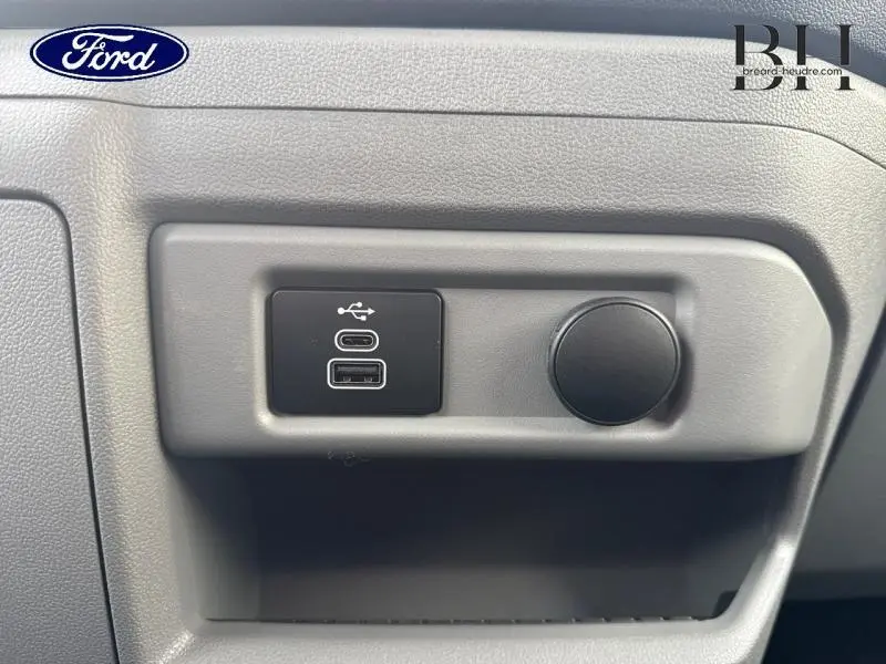 Détail intérieur montrant les prises USB et prise 12V sur la console du Ford Transit Custom Fourgon gris lunaire.