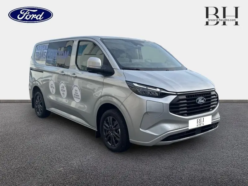 Ford Transit Custom Fourgon gris lunaire métallisé, vue 3/4 avant droit avec jantes gris carbone et vitres latérales teintées.