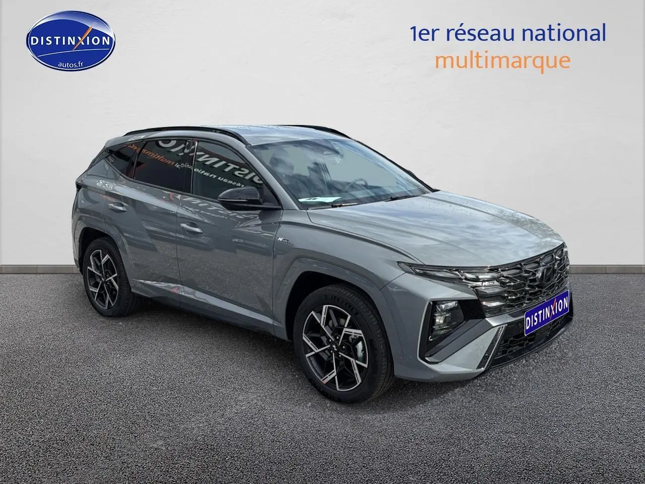 Vue 3/4 avant du Hyundai Tucson 2026 gris Shadow avec calandre noire brillante et jantes alliage 19 pouces.