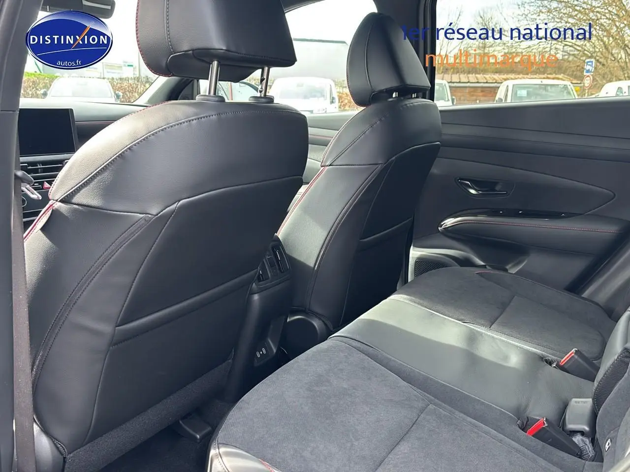 Vue intérieure arrière côté droit du Hyundai Tucson 2026, sièges en cuir noir avec surpiqûres rouges et garnitures modernes.
