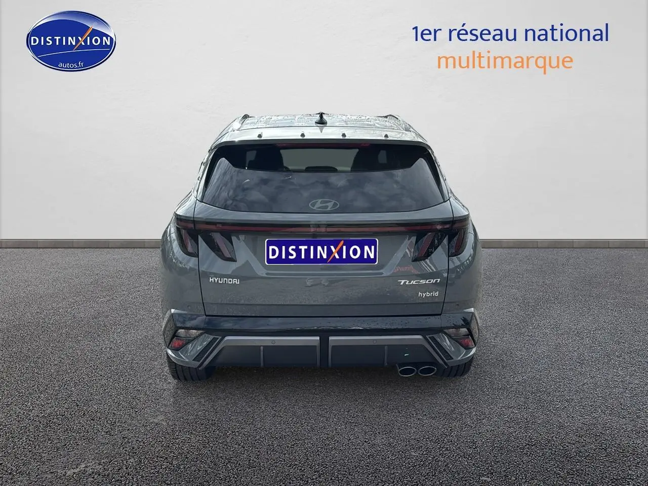 Vue arrière d'un Hyundai Tucson hybride gris shadow avec feux arrière LED et double sortie d'échappement à droite.