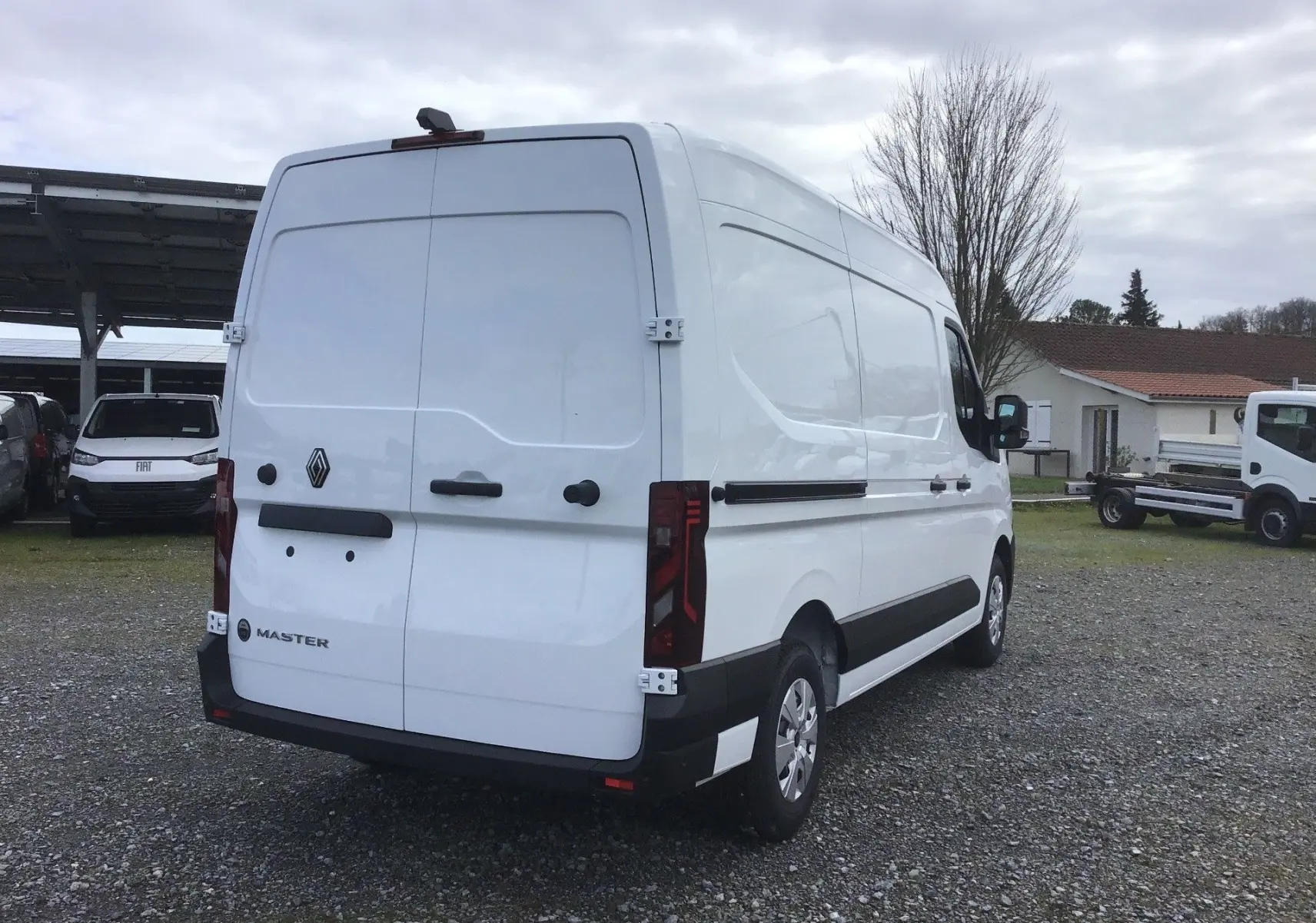Vue 3/4 arrière droite d’un Renault Master blanc, fourgon utilitaire avec portes arrière fermées et détails noirs contrastants.