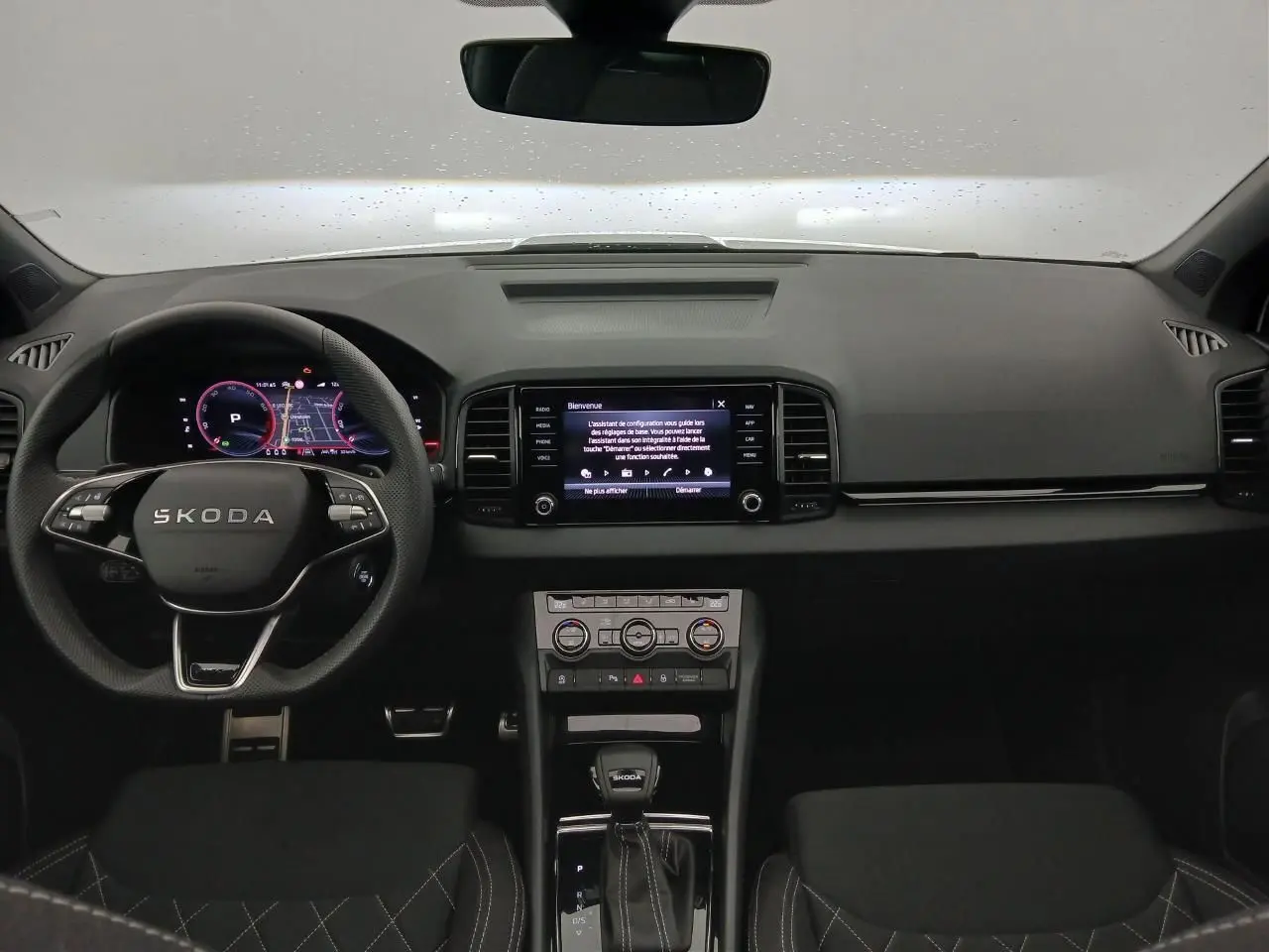 Vue intérieure frontale du tableau de bord et volant SKODA KAROQ 1.5 TSI 150 DSG7 SPORTLINE 2025, ambiance noire moderne.