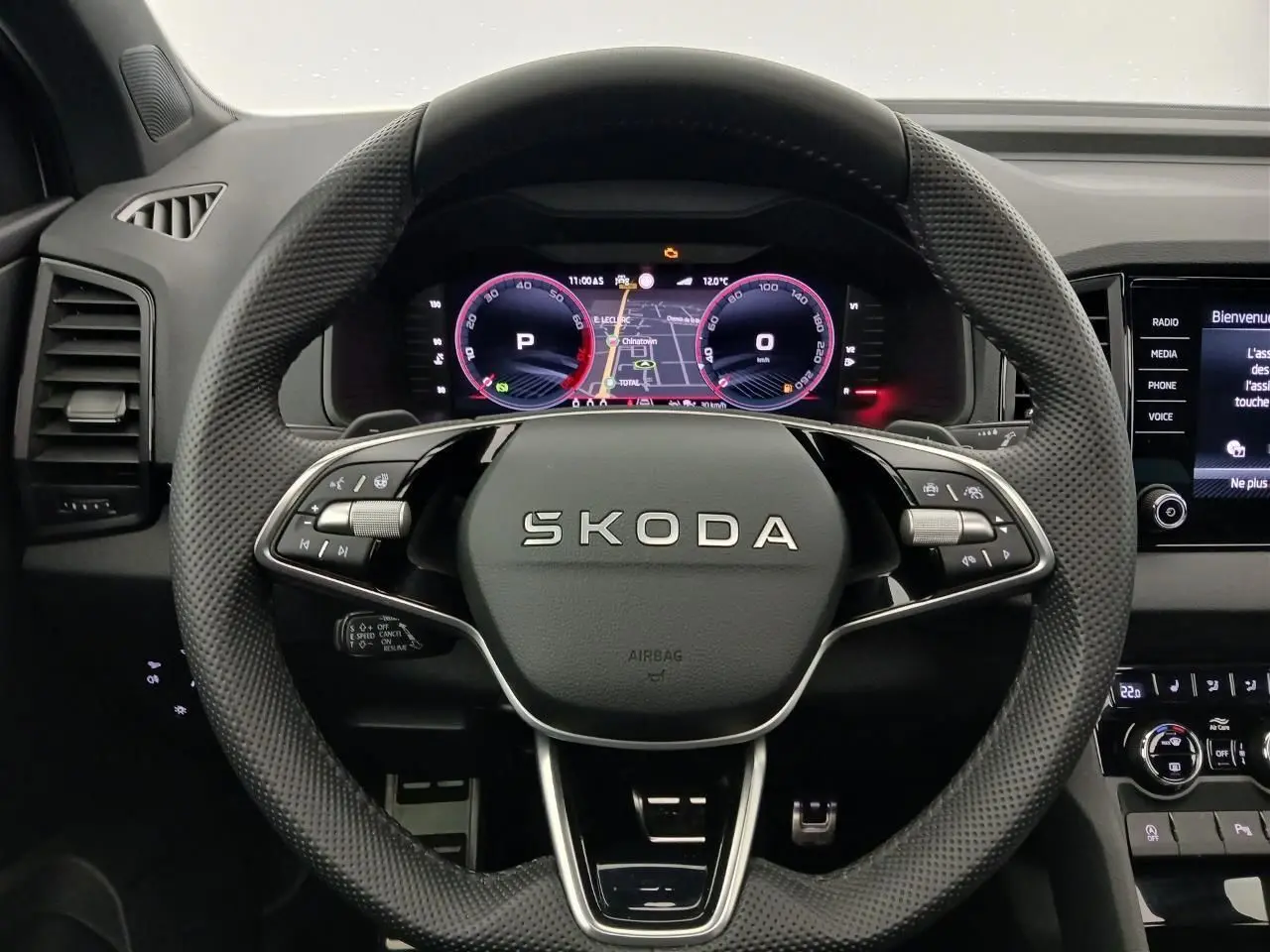 Vue intérieure centrée sur le volant perforé du Skoda Karoq 2025 avec tableau de bord numérique et commandes intégrées.
