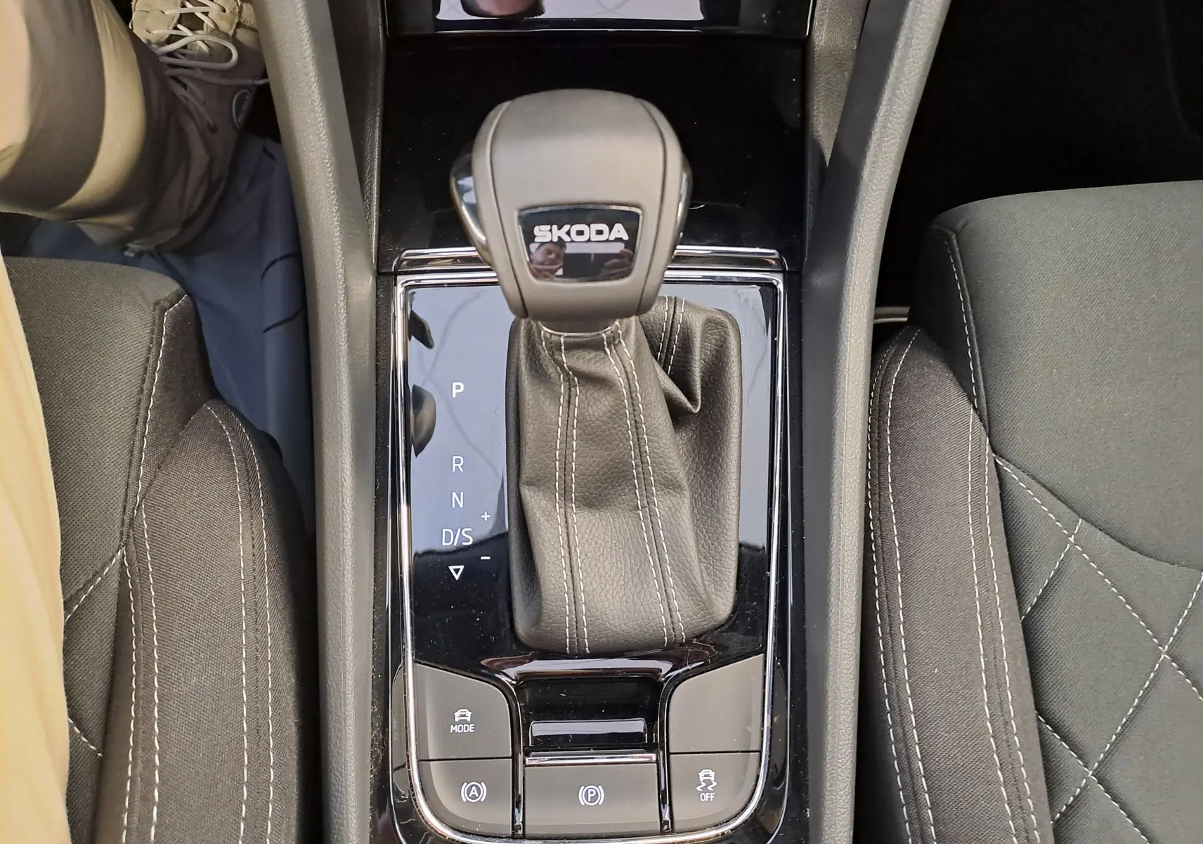 Vue plongeante sur la console centrale du Skoda Karoq 2025 blanc lune, mettant en valeur le levier de vitesse automatique et les sièges noirs.