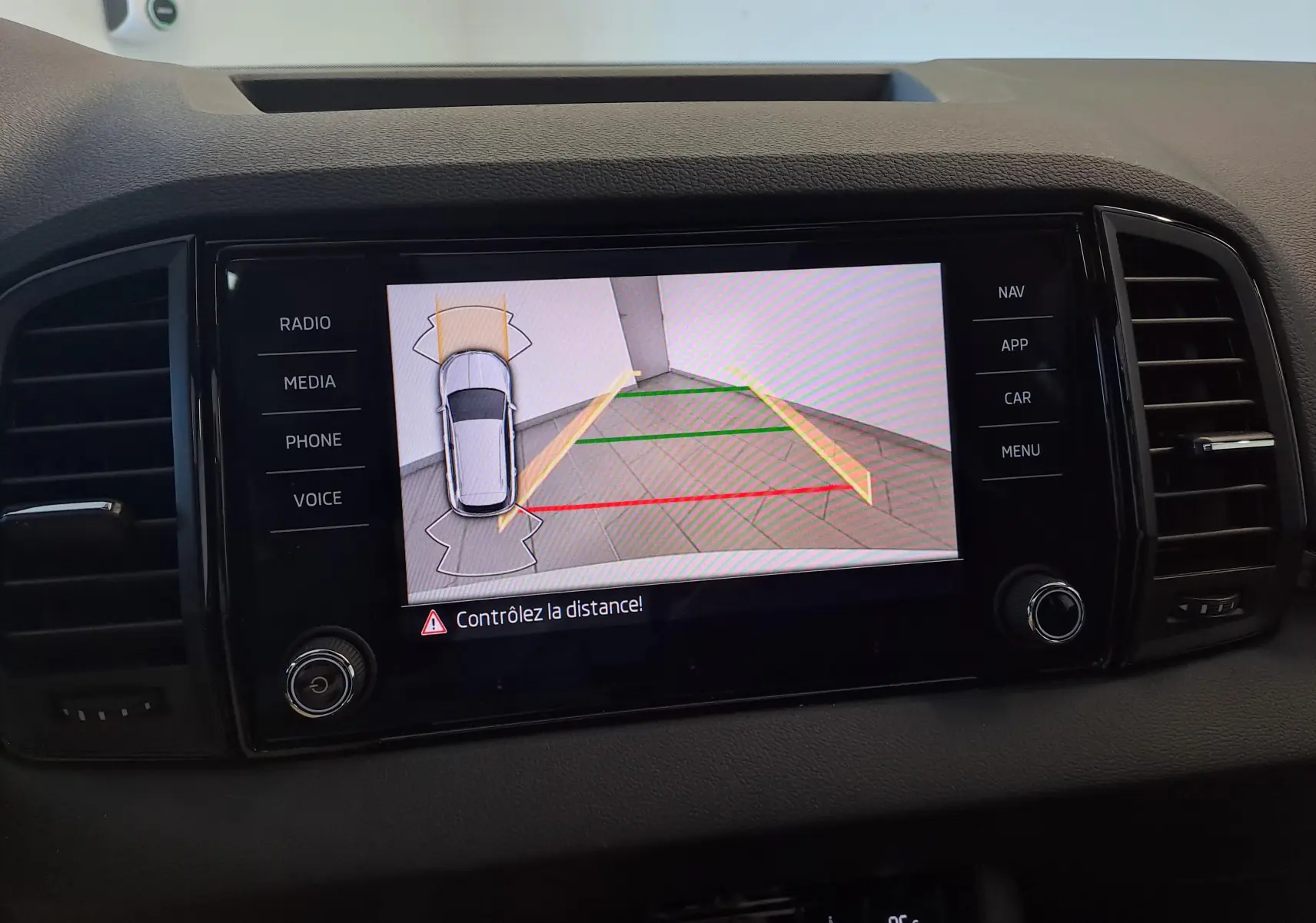 Écran central du Skoda Karoq 2025 blanc lune montrant la caméra de recul avec guidage de stationnement.