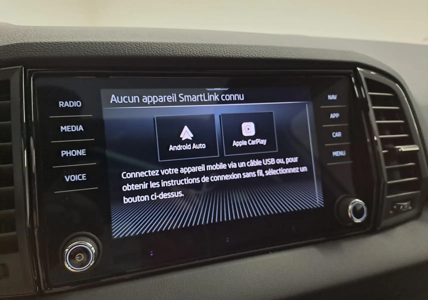 Écran tactile central du Skoda Karoq 2025 affichant les options Android Auto et Apple CarPlay, entouré de boutons noirs.