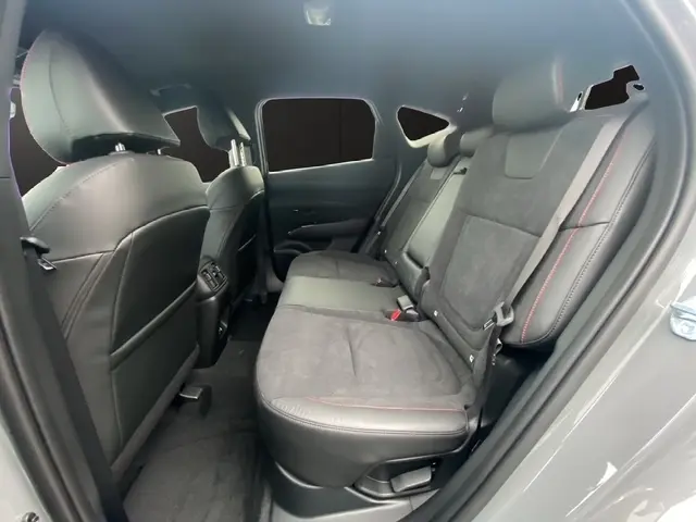 Vue intérieure côté gauche des sièges arrière en cuir noir avec surpiqûres rouges du Hyundai Tucson 1.6 Hybrid 2026 gris foncé.