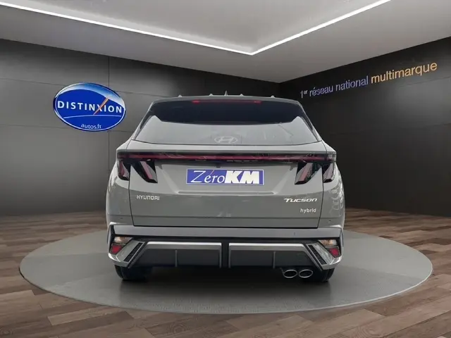 Vue arrière d’un Hyundai Tucson gris foncé hybride 2026 avec hayon motorisé et double sortie d’échappement visible.