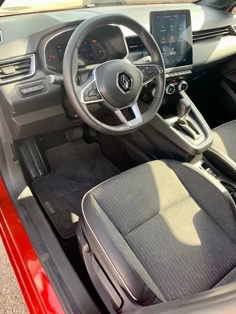Intérieur de la Renault Clio V rouge, vue côté conducteur, volant multifonction et écran tactile central visible