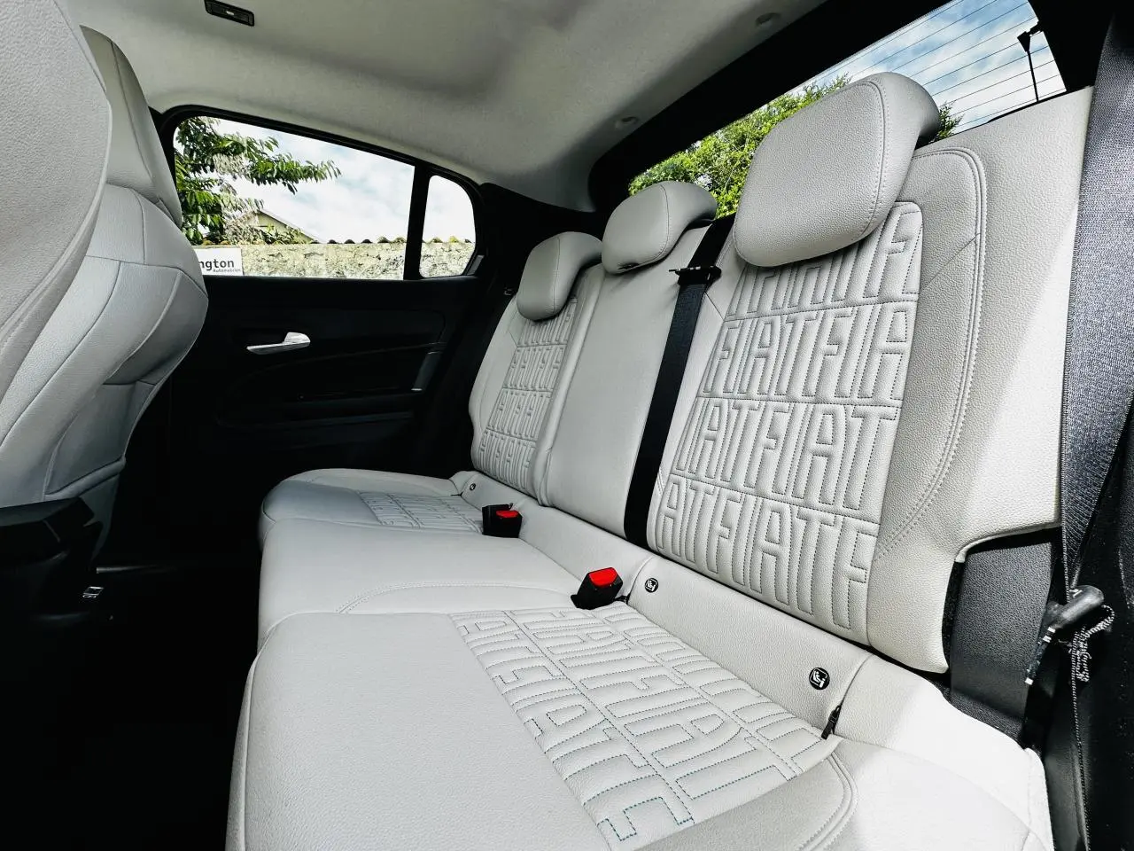 Vue intérieure côté droit des sièges arrière ivoire soft touch avec monogrammes FIAT embossés sur la Fiat 600 hybride 2024.