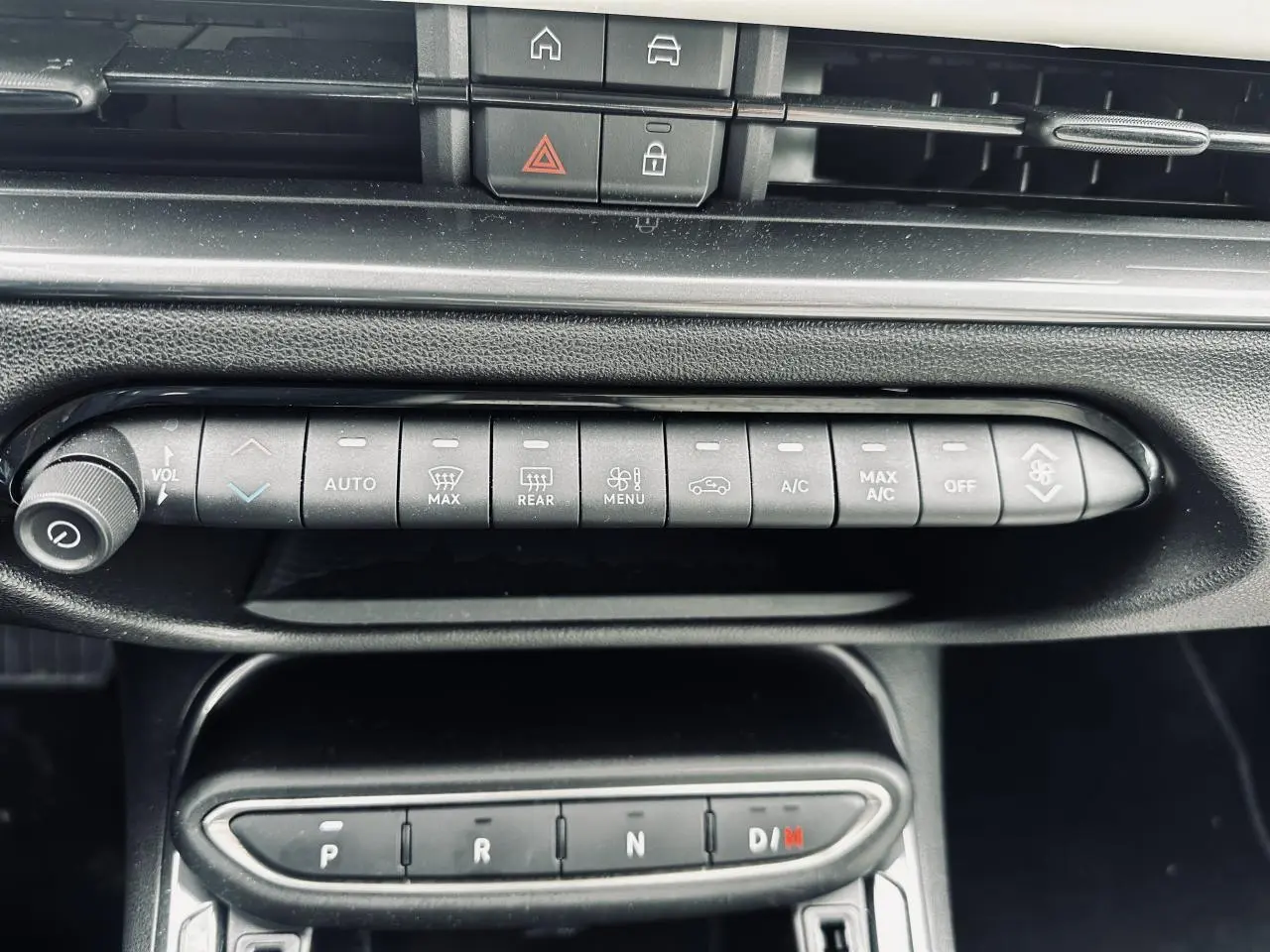 Gros plan sur la console centrale de la Fiat 600 La Prima 2024, montrant les commandes de climatisation et la boîte auto noire.