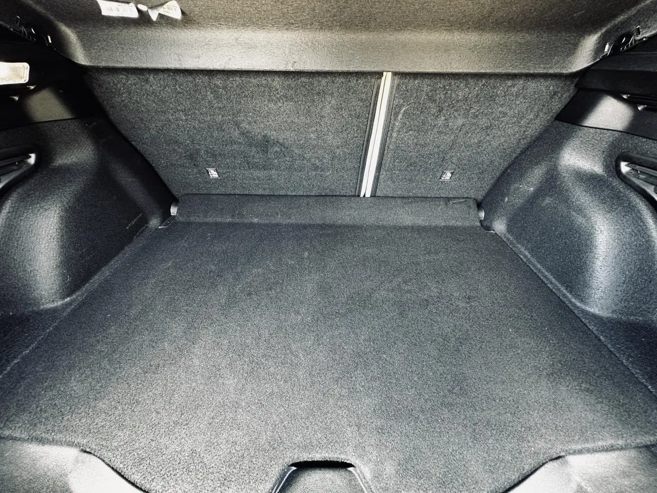 Coffre spacieux de la FIAT 600 1.2 Hybrid La Prima 2024, vue intérieure avec banquette arrière rabattue, revêtement noir.