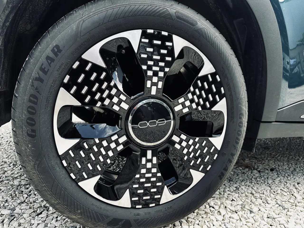 Gros plan sur la roue avant droite d'une FIAT 600 bleu clair avec jante au design noir et argenté.