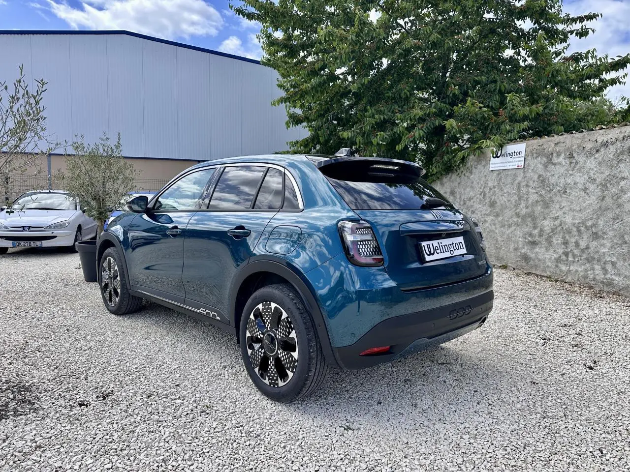 Vue 3/4 arrière droite d'une FIAT 600 hybride bleu clair avec feux arrière à LED et jantes stylisées.