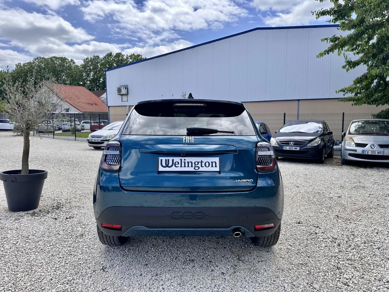 Vue arrière d'une FIAT 600 hybride bleu clair avec feux arrière LED et logo FIAT visible sur un parking.
