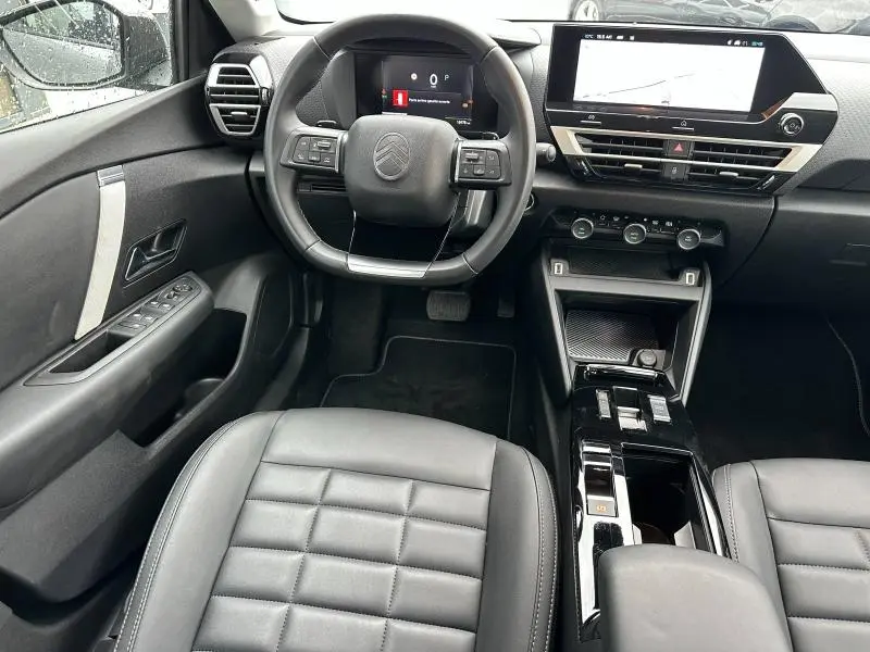 Intérieur de la Citroën C4 X 2025 vu de face, montrant le tableau de bord numérique et la console centrale noire brillante.