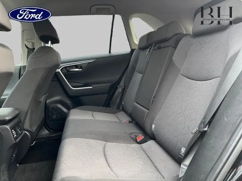 Vue intérieure côté droit des sièges arrière en tissu noir du Toyota RAV4 2.5 Hybride 2022 avec accoudoir central.