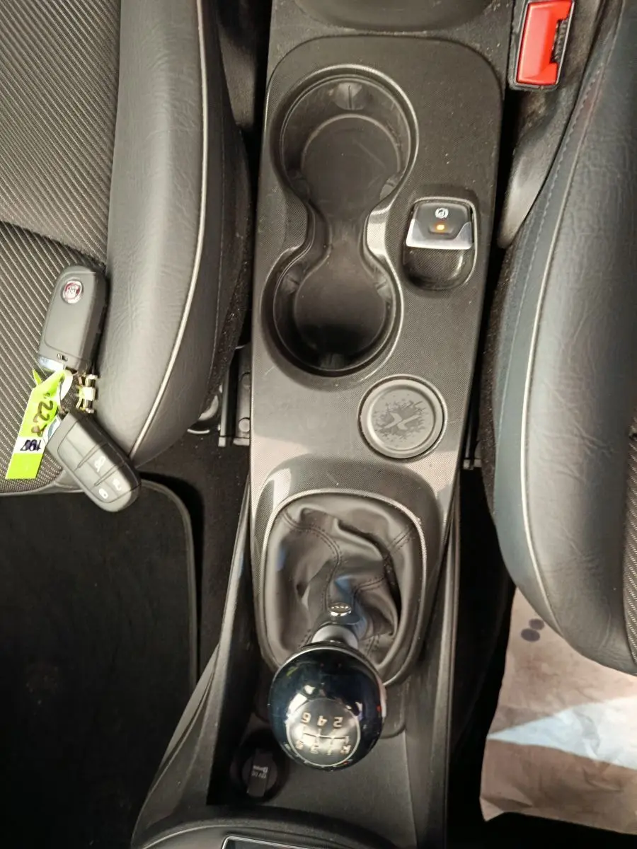 Vue plongeante sur la console centrale noire d'une Fiat 500X 2020 avec levier de vitesse manuel et porte-gobelets.